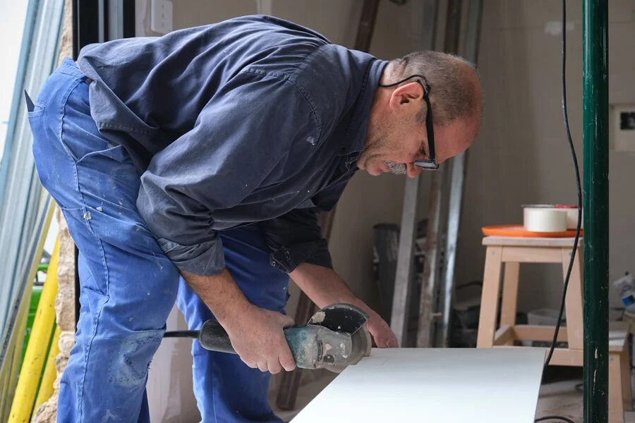 A man using power tool on sheet material.